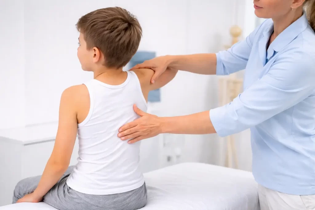 Osteopatie v REHANEST dětské rehabilitaci Praha Barrandov – terapeutka v bílém provádí jemnou manuální terapii zad u chlapce v ordinaci.